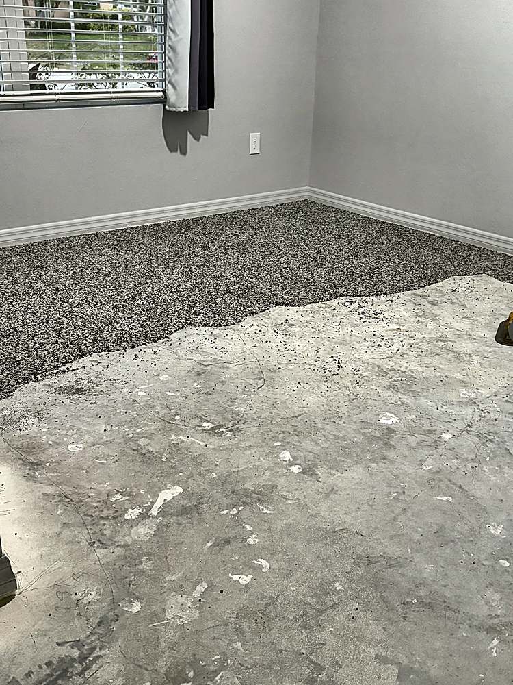 Interior room mid-installation, stone carpet going down over bare concrete