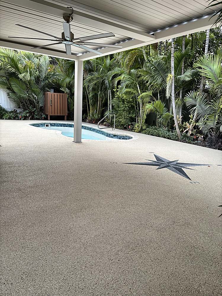 Covered pool deck finished in a light Vuba Stone blend with a custom compass rose inlay