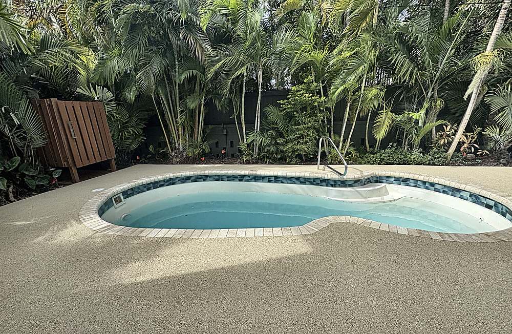 Finished pool deck in a tropical garden, warm Vuba Stone blend